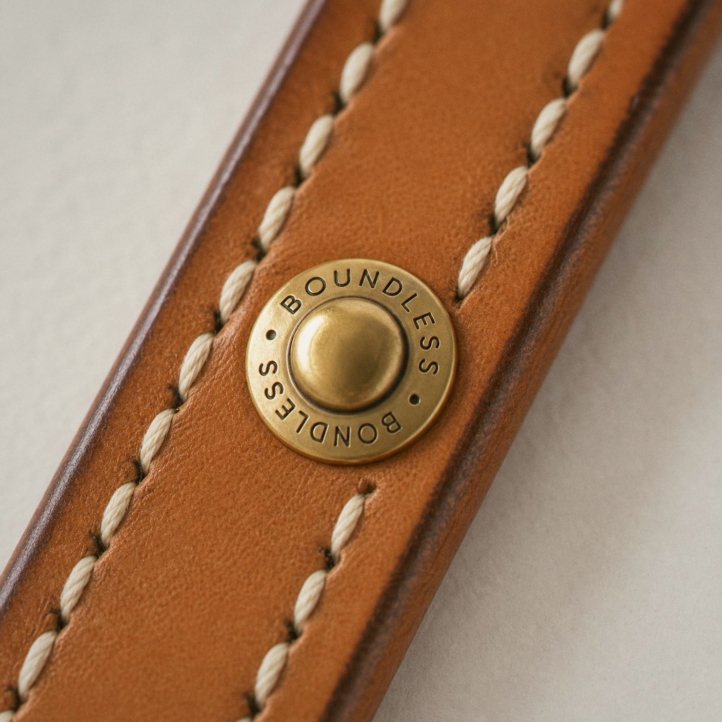 The brass stud engraved BOUNDLESS on natural bridle leather.